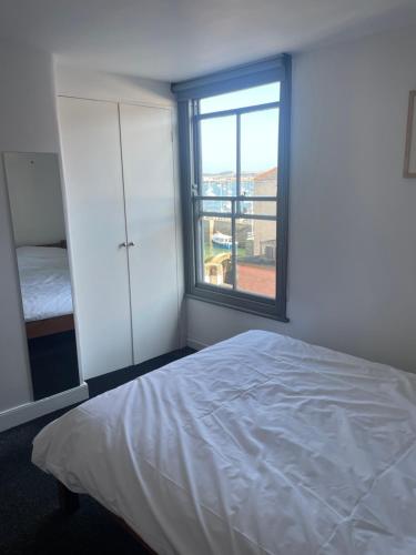 a white bedroom with a bed and a window at Bright spacious flat in the heart of town in Falmouth