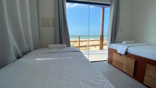 a bedroom with two beds and a view of the ocean at Galinhos Kite House in Galinhos