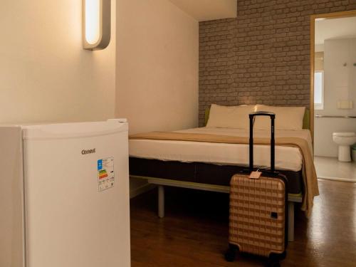 a small bedroom with a bed with a refrigerator at ibis budget Sao Paulo Paraiso in Sao Paulo