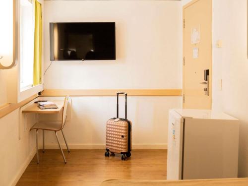 a room with a suitcase and a desk and a television at ibis budget Sao Paulo Paraiso in Sao Paulo