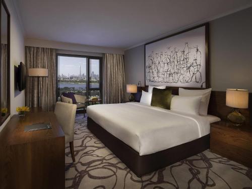 a hotel room with a large bed and a desk at Pullman Dubai Creek City Centre Residences in Dubai