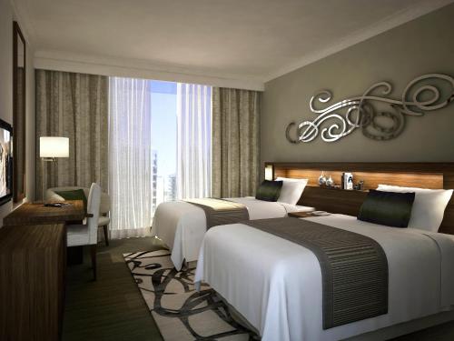 a hotel room with two beds and a desk at Pullman Dubai Creek City Centre Residences in Dubai