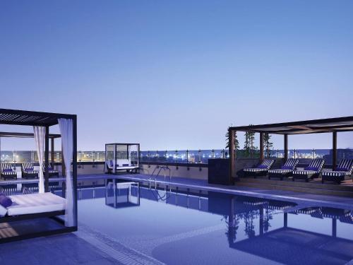 a swimming pool with chairs on the roof of a building at Pullman Dubai Creek City Centre Residences in Dubai