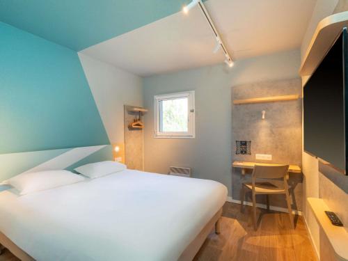 a bedroom with a bed and a desk and a window at ibis budget Nantes Sainte Luce - Hôtel Rénové in Sainte-Luce-sur-Loire