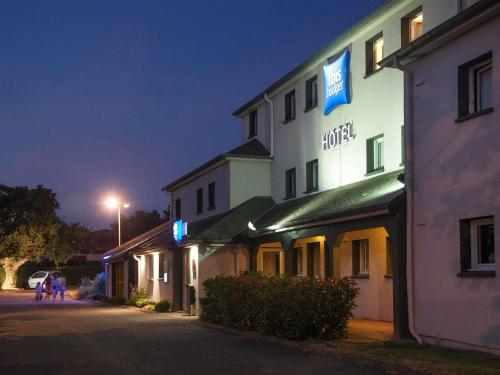 a hotel building at night with people walking down a street at ibis budget Nantes Sainte Luce - Hôtel Rénové in Sainte-Luce-sur-Loire