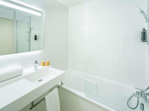 a white bathroom with a white tub and a sink at ibis budget Nantes Sainte Luce - Hôtel Rénové in Sainte-Luce-sur-Loire