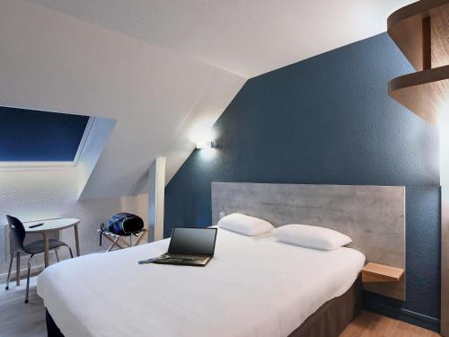 a hotel room with a bed with a laptop on it at ibis budget Vannes in Vannes