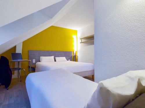 a hotel room with two beds and a yellow wall at ibis budget Vannes in Vannes