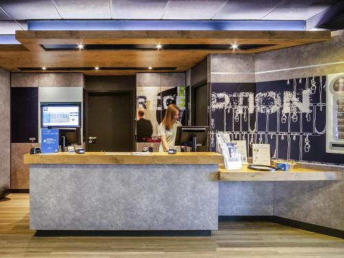 a woman standing at the counter of a restaurant at ibis Budget Courbevoie Paris La Défense in Courbevoie
