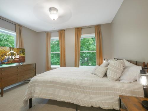 Schlafzimmer mit einem Bett, einem TV und Fenstern in der Unterkunft Cozy 3BR Retreat Near Killington Resort - Fireplace, Pet Friendly in Sherburne Center