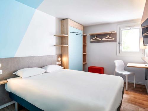 a bedroom with a bed and a desk and a table at ibis budget Bayonne in Bayonne