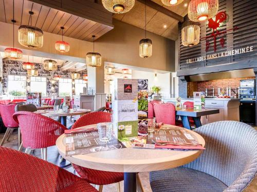 a restaurant with red chairs and tables and a counter at ibis budget Bayonne in Bayonne