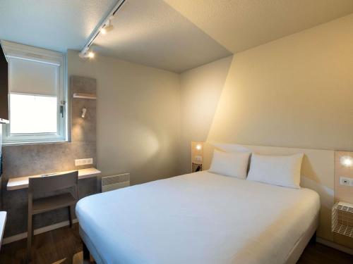 a bedroom with a large white bed and a window at ibis budget Rennes Chantepie - Hôtel rénové in Chantepie