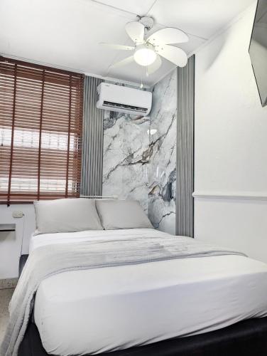 a bedroom with a white bed and a stone wall at Hostal Yoha in Panama City