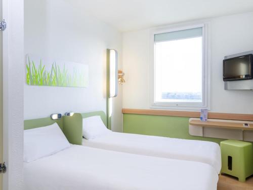 two beds in a room with a tv and a window at ibis budget Lyon Gerland in Lyon