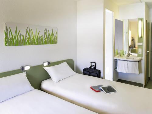 a bedroom with two beds with a sink and a mirror at ibis budget Lyon Gerland in Lyon
