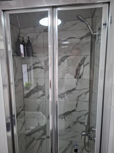 una ducha con puerta de cristal en un baño en Private Fully Furnished Studio Flat!, en Luton