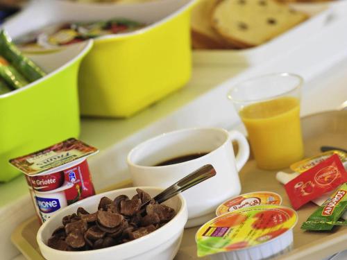 a tray with a cup of coffee and a bowl of food at ibis Budget Caen Centre Gare in Caen