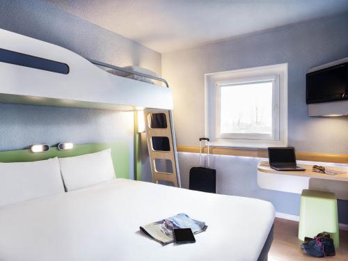 a bedroom with a bed and bunk beds and a window at Ibis Budget Cergy St Christophe in Cergy