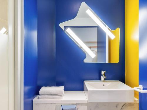 a blue bathroom with a sink and a mirror at Ibis Budget Cergy St Christophe in Cergy
