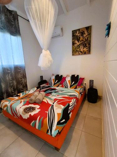 a bedroom with a bed with a colorful comforter at Kaz a Klemence Gite creole avec piscine et table dhotes a Anse Bertrand in Anse-Bertrand