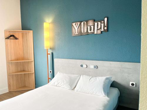 a bedroom with a white bed and a blue wall at Ibis Budget Saint Christol Les Alès in Saint-Christol-lès-Alès