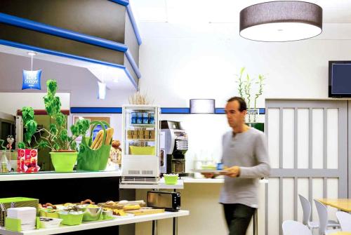 a man standing in a kitchen with a plate of food at Ibis Budget Saint Christol Les Alès in Saint-Christol-lès-Alès