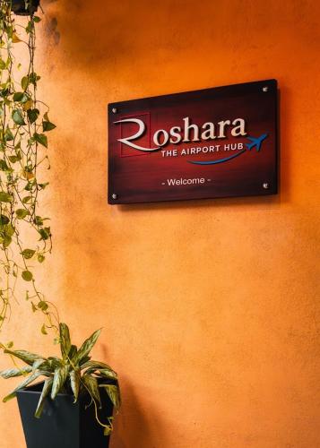 a sign on the side of a wall with a plant at Roshara The Airport Hub in Katunayake