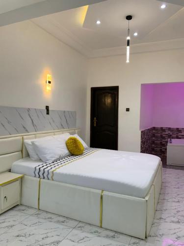 a bedroom with a large white bed with yellow pillows at Appart'hotel avec jacuzzi à Adjarra in Adjarra
