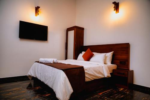 a bedroom with two beds and a television on the wall at Roshara The Airport Hub in Katunayake