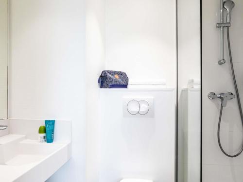 a white bathroom with a shower and a sink at ibis budget Paris Porte de Montreuil in Montreuil