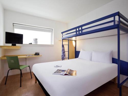 a bedroom with a bed with a book and a chair at ibis budget Paris Porte de Montreuil in Montreuil