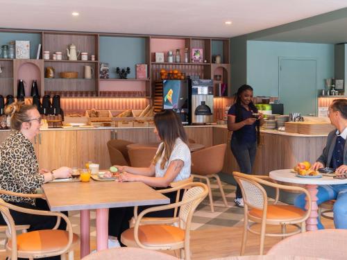 a group of people sitting at tables in a restaurant at ibis budget Marne la Vallée Val d'Europe in Montévrain