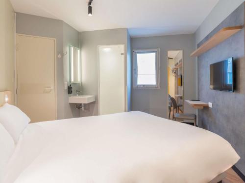 a bedroom with a large white bed and a sink at ibis budget Marne la Vallée Val d'Europe in Montévrain