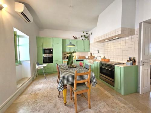 a kitchen with green cabinets and a table and chairs at Eco-Villa Monte Do Barrocalinho in Loulé