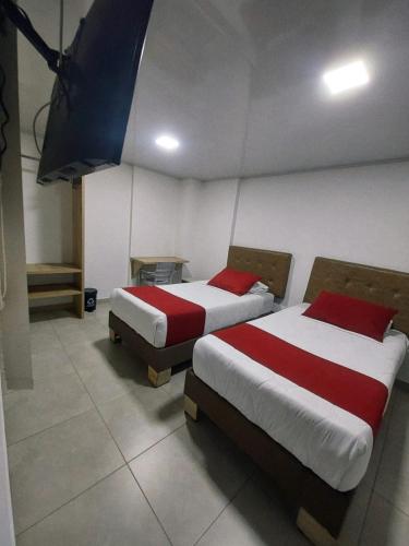 two beds in a room with red and white sheets at Hotel Monarka-Edificio in Popayan
