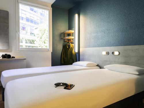 two beds with a pair of shoes sitting on top of them at ibis budget Bordeaux Centre - Gare Saint Jean in Bordeaux