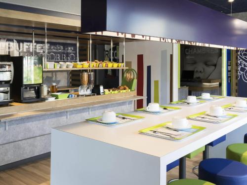 a kitchen with a counter with tables and chairs at Hotel Ibis Budget Lyon Eurexpo - in Chassieu