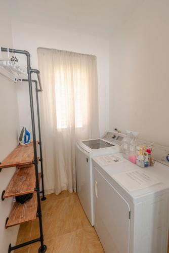 a laundry room with a washing machine and a shelf at The Hidden Cottage in Welches Hill