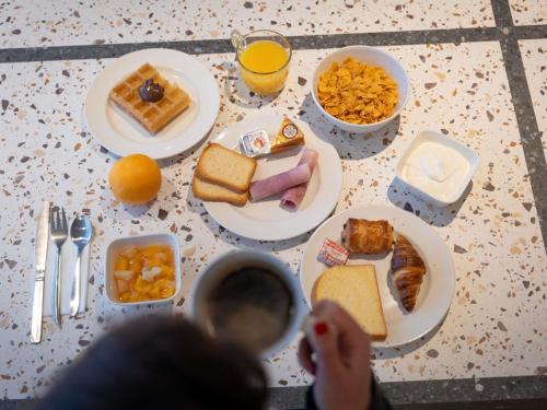 a table with plates of breakfast food on it at Hotel Ibis Budget Rennes Cesson in Cesson-Sévigné