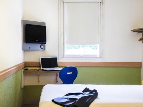 a room with a bed and a laptop and a window at ibis budget Issoire in Issoire