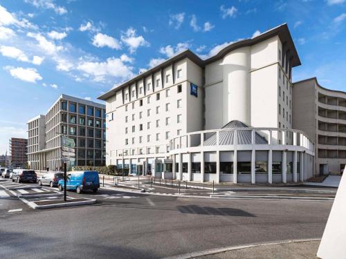 a large white building with cars parked in front of it at ibis budget Lyon Villeurbanne in Villeurbanne