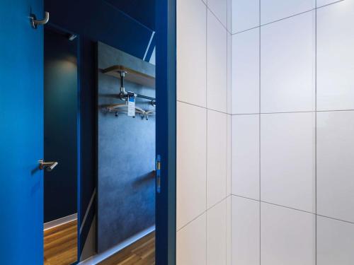 a bathroom with a blue door and white tiles at ibis budget Lyon Villeurbanne in Villeurbanne
