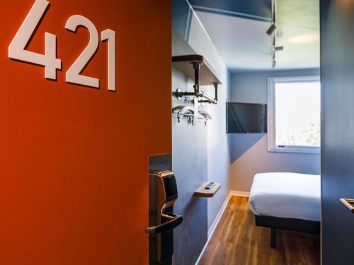 a room with a bed and a sign on the wall at ibis budget Lyon Villeurbanne in Villeurbanne