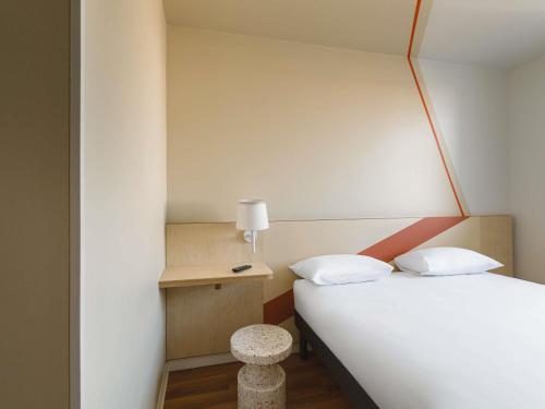 a bedroom with a white bed and a table with a lamp at ibis budget Lyon Villeurbanne in Villeurbanne