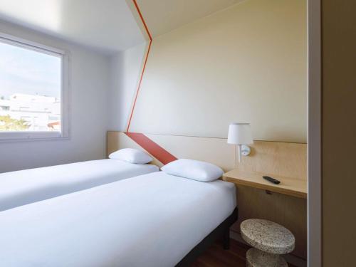 a hotel room with two beds and a window at ibis budget Lyon Villeurbanne in Villeurbanne