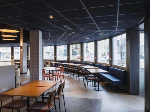a restaurant with tables and chairs and windows at ibis budget Lyon Villeurbanne in Villeurbanne