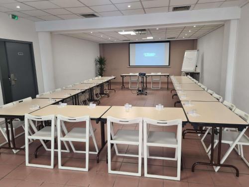 a conference room with tables and chairs and a screen at Ibis Budget Toulon Centre in Toulon