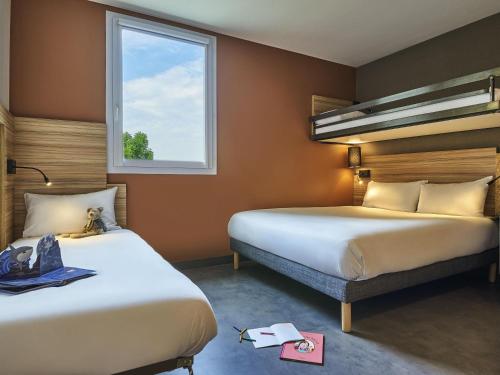 a hotel room with two beds and a window at Greet Hotel Paris porte de la Chapelle - Aréna in Paris