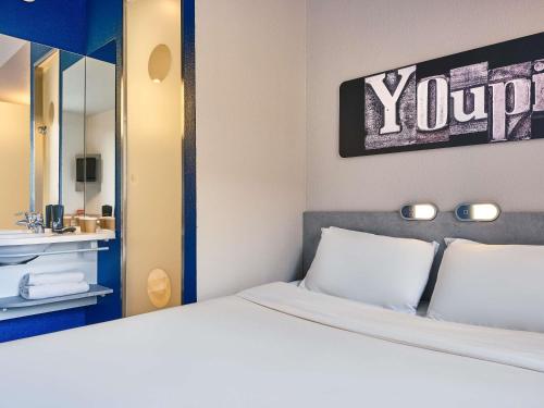 a bedroom with a white bed and a mirror at Ibis Budget Vélizy in Vélizy-Villacoublay
